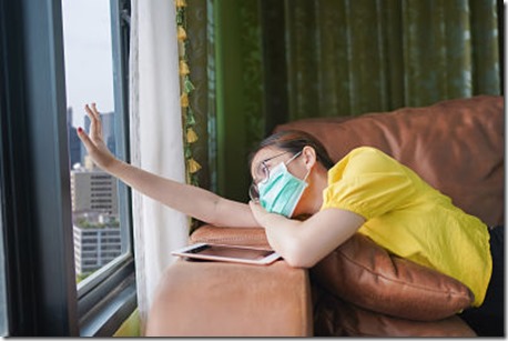 Young asian woman isolating at home with tablet on the sofa in the living room. She is bored because stay at home campaign for coronavirus prevention.