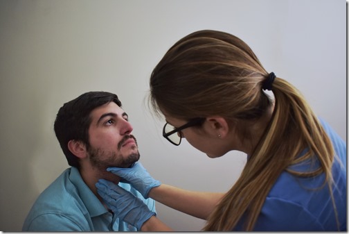 Clinician palpating patient's neck during a physical exam