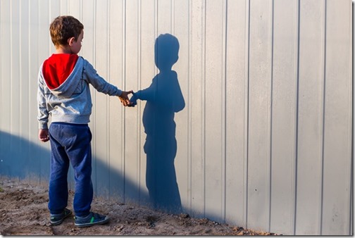 boy and his shadow. Lonely little child playing with his shadow outside. imaginary friend. the concept of autism and loneliness. Copy space for your text