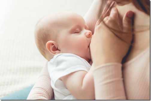 cropped view of mother breastfeeding her child in apartment 