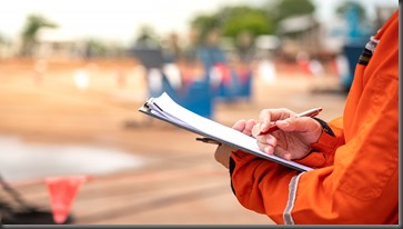 Action of safety officer is writing and check on checklist document during safety audit and inspection at drilling site operation. Industrial expertise occupation working scene.