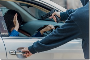 Robber threatened driver car on street. Thief use gun to intimidate asian woman for give car key. Give rob car key by thief cover face with black mask, intimidate by pointing gun.