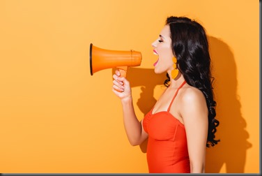 profile of young woman in swimsuit screaming in megaphone on orange