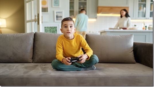 Boy kid playing video computer game at home living room