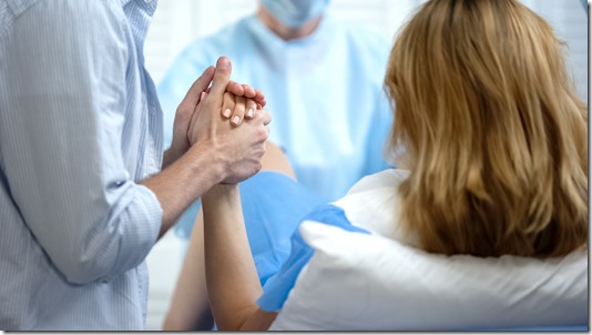 Close-up of man holding wife hand for support during pushing to give childbirth