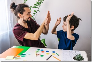 Happy autism boy during therapy with school tutor, learning and having fun together