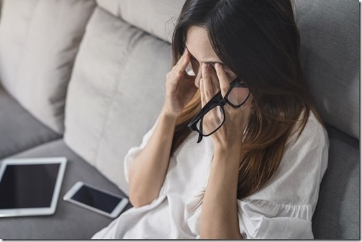 Young woman take off her glasses and siiting on sofa