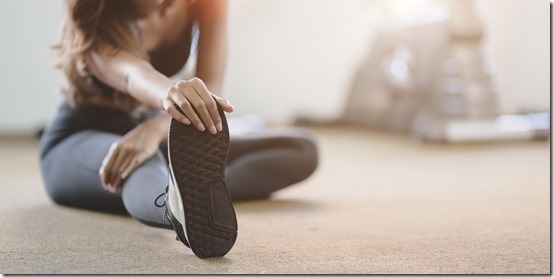 Beautiful Asian woman with tan and slim body stretching legs before exercise