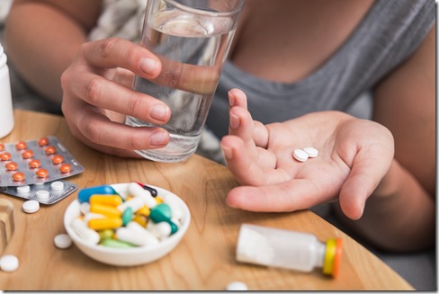 Young woman sick with colds and flu, self-medication at home with vitamins and pills