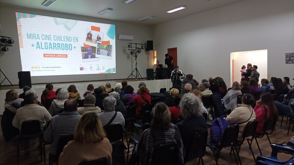 Vecinos de Algarrobo asistiendo a una función de cine chileno en un centro comunitario